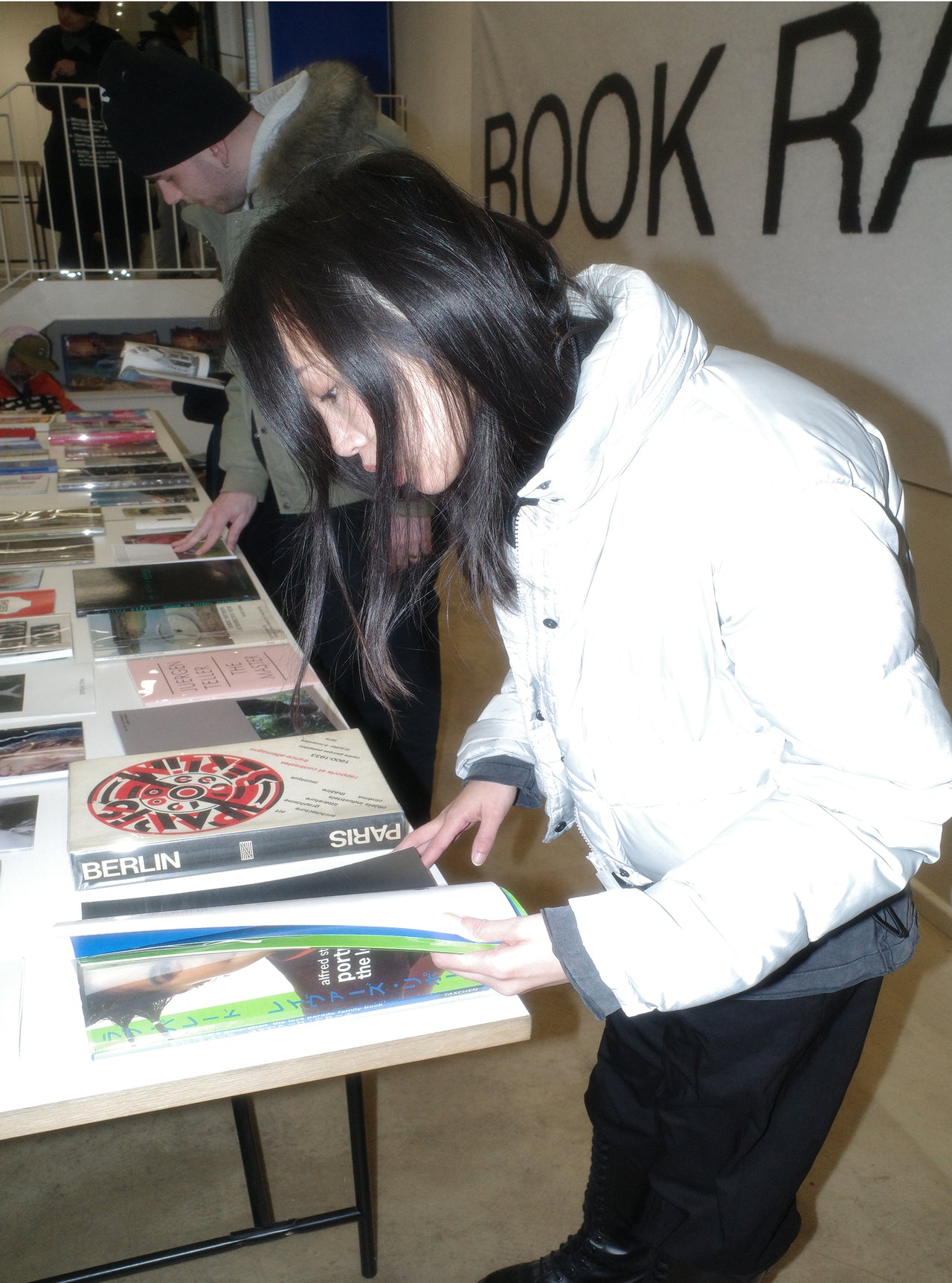 at OBEY art space Berlin; tow people looking at books that are displayed on a table.