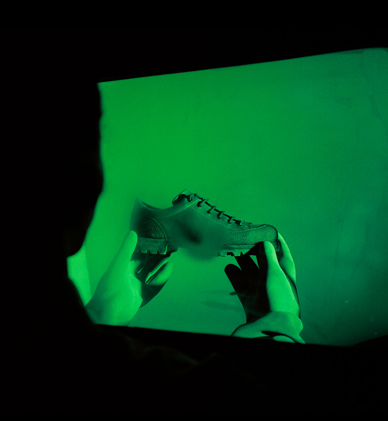 Image of model holding the Paraboot x Obey in front of green cube.