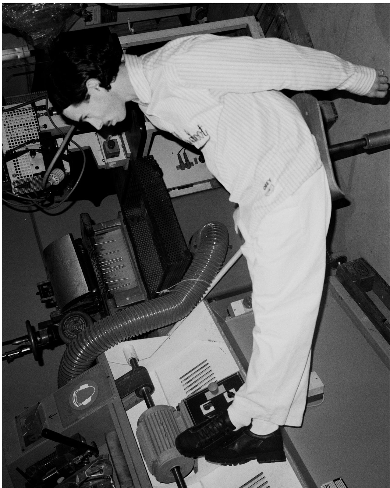 black and white image of model on a chair in a factory.