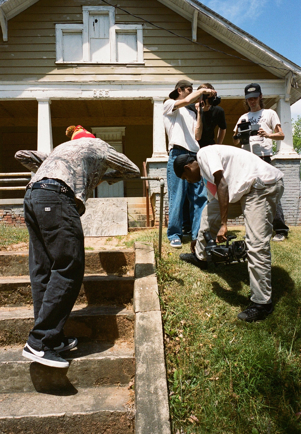 Group of people filming a scene outside a house.